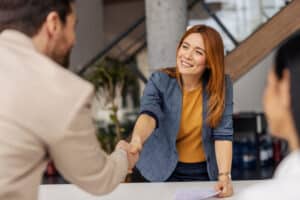 Portrait of friendly female boss shaking hands with new team member on sprint meeting.